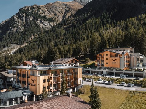 Bilder aus der Sportalm Hotelgebäude umgeben von Bergen und Wäldern an einem sonnigen Tag