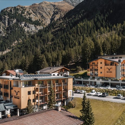Pictures from Sportalm Hotel buildings surrounded by mountains and forests on a sunny day