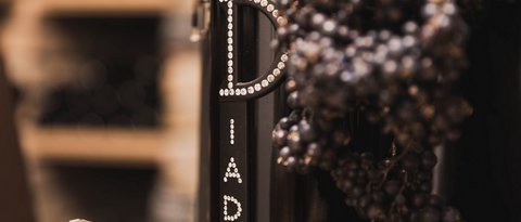 Bilder aus der Sportalm Weinflasche neben Trauben und Korken in einer warmen Atmosphäre