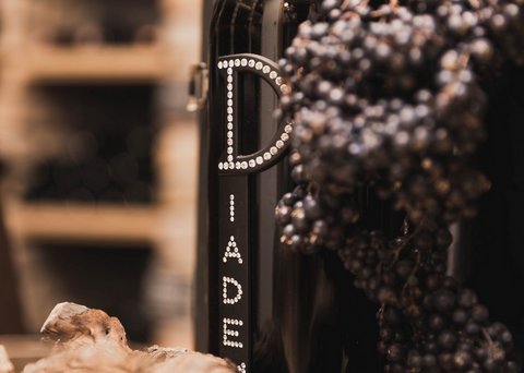 Bilder aus der Sportalm Weinflasche neben Trauben und Korken in einer warmen Atmosphäre