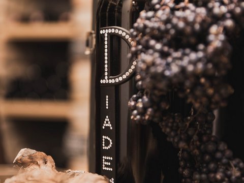 Pictures from Sportalm Wine bottle next to grapes and cork in a warm setting