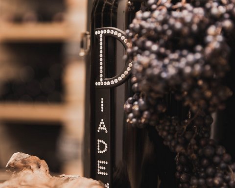 Bilder aus der Sportalm Weinflasche neben Trauben und Korken in einer warmen Atmosphäre