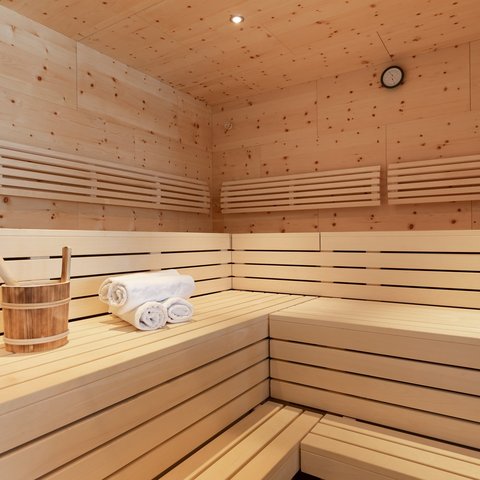 Bilder aus der Sportalm Innenraum einer Sauna mit Holzbank, Handtüchern und Holzeimer