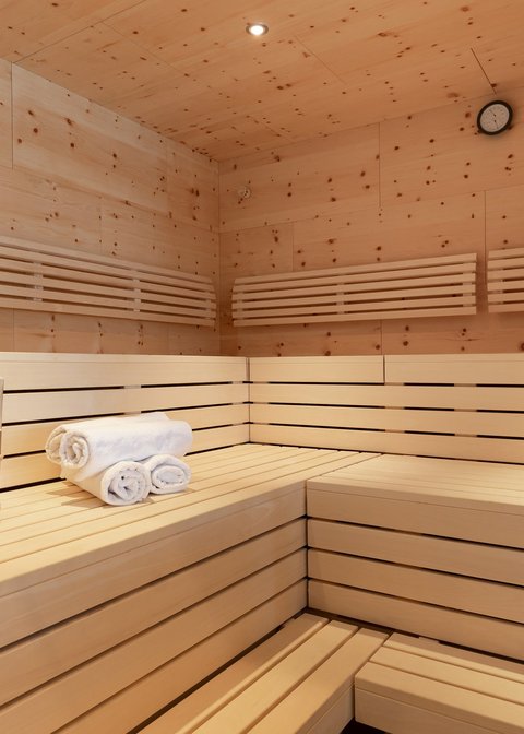 Bilder aus der Sportalm Innenraum einer Sauna mit Holzbank, Handtüchern und Holzeimer