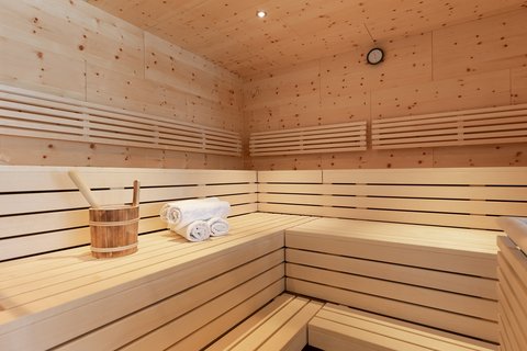 Bilder aus der Sportalm Innenraum einer Sauna mit Holzbank, Handtüchern und Holzeimer