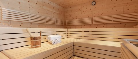 Bilder aus der Sportalm Innenraum einer Sauna mit Holzbank, Handtüchern und Holzeimer