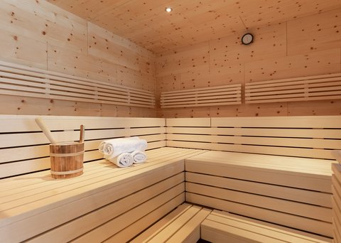 Bilder aus der Sportalm Innenraum einer Sauna mit Holzbank, Handtüchern und Holzeimer