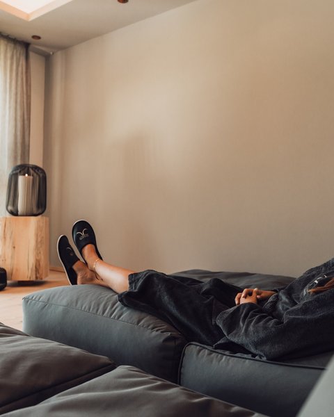 Bilder aus der Sportalm Frau entspannt sich auf Sofa in hellem Raum mit Kerzenlicht