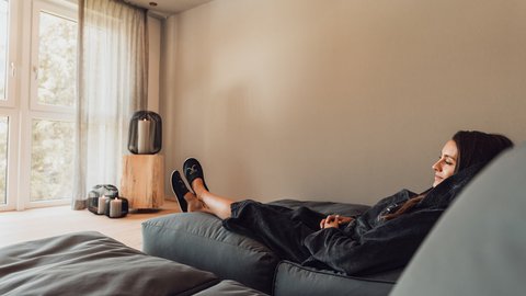 Pictures from Sportalm Woman relaxing on sofa in bright room with candle lights
