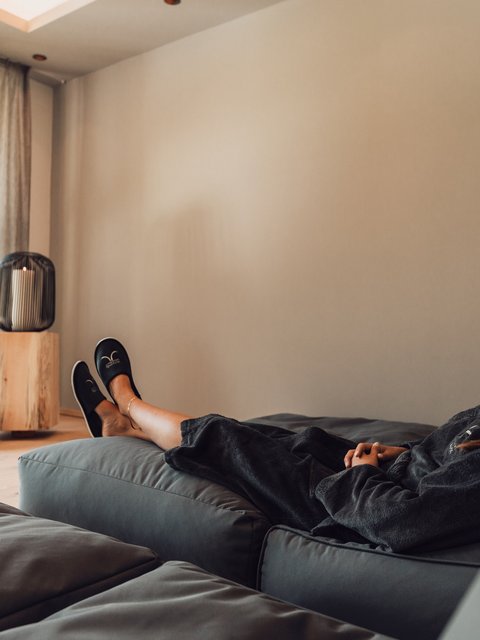 Bilder aus der Sportalm Frau entspannt sich auf Sofa in hellem Raum mit Kerzenlicht