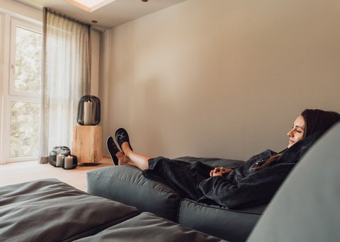 Bilder aus der Sportalm Frau entspannt sich auf Sofa in hellem Raum mit Kerzenlicht