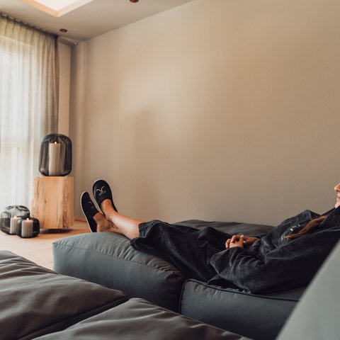 Bilder aus der Sportalm Frau entspannt sich auf Sofa in hellem Raum mit Kerzenlicht