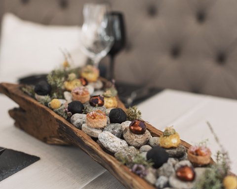 Bilder aus der Sportalm Vorspeisen auf Steinen in einem rustikalen Holztablett serviert