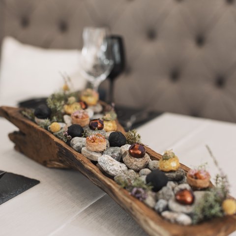 Bilder aus der Sportalm Vorspeisen auf Steinen in einem rustikalen Holztablett serviert