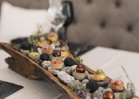 Bilder aus der Sportalm Vorspeisen auf Steinen in einem rustikalen Holztablett serviert