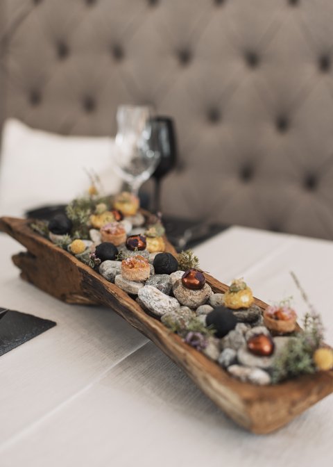 Bilder aus der Sportalm Vorspeisen auf Steinen in einem rustikalen Holztablett serviert