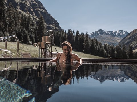 Bilder aus der Sportalm Frau entspannt im Pool mit Bergpanorama im Hintergrund