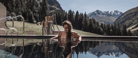 Bilder aus der Sportalm Frau entspannt im Pool mit Bergpanorama im Hintergrund