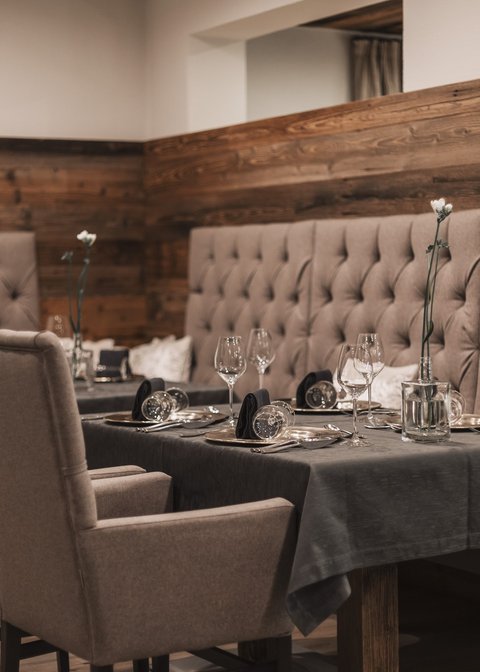 Bilder aus der Sportalm Eleganter Esstisch mit Stühlen und dunkelgrauem Tischset in gemütlichem Restaurant
