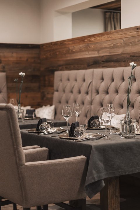 Bilder aus der Sportalm Eleganter Esstisch mit Stühlen und dunkelgrauem Tischset in gemütlichem Restaurant