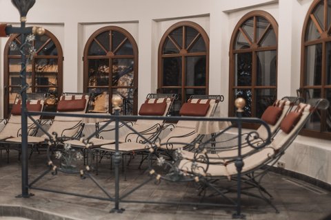 Bilder aus der Sportalm Mehrere gepolsterte Loungesessel vor bogenförmigen Fenstern in einem Innenraum