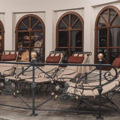 Bilder aus der Sportalm Mehrere gepolsterte Loungesessel vor bogenförmigen Fenstern in einem Innenraum