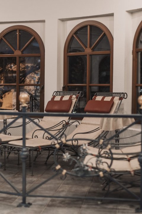 Bilder aus der Sportalm Mehrere gepolsterte Loungesessel vor bogenförmigen Fenstern in einem Innenraum