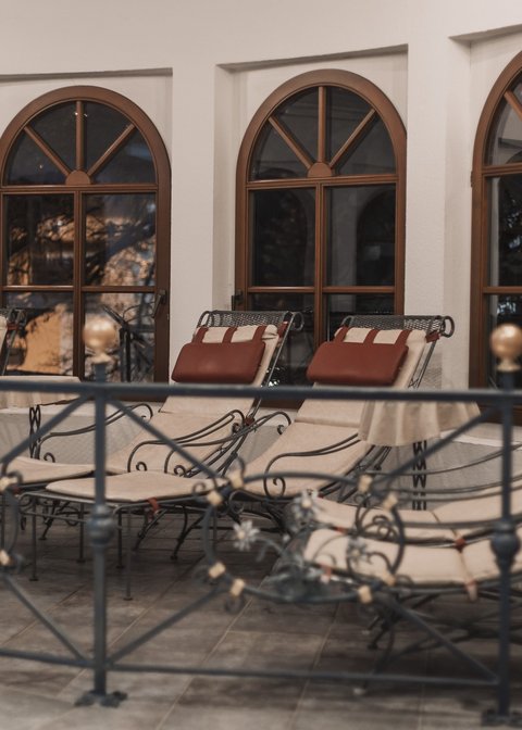 Bilder aus der Sportalm Mehrere gepolsterte Loungesessel vor bogenförmigen Fenstern in einem Innenraum