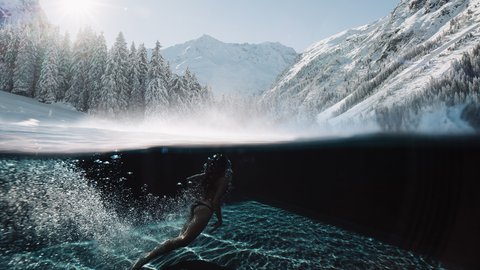 Pictures from Sportalm Woman swimming in clear water with snowy mountains and sunlight in background