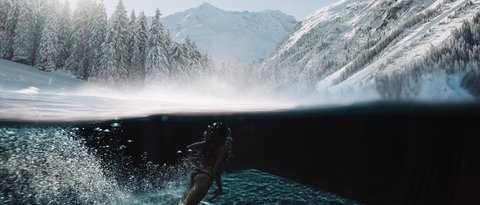Pictures from Sportalm Woman swimming in clear water with snowy mountains and sunlight in background