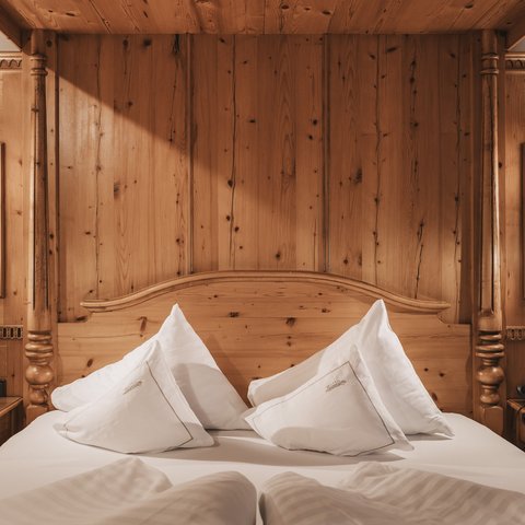Bilder aus der Sportalm Gemütliches Holzbett mit weißen Kissen und Nachttischen mit Lampen