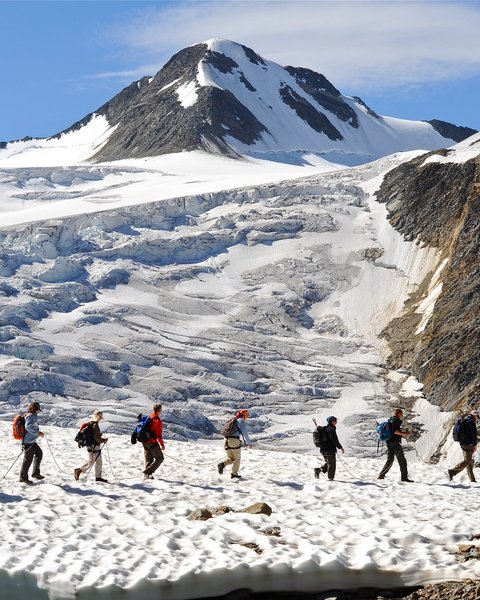 Bilder aus der Sportalm Gruppe von Wanderern auf verschneitem Bergpfad mit Berg im Hintergrund