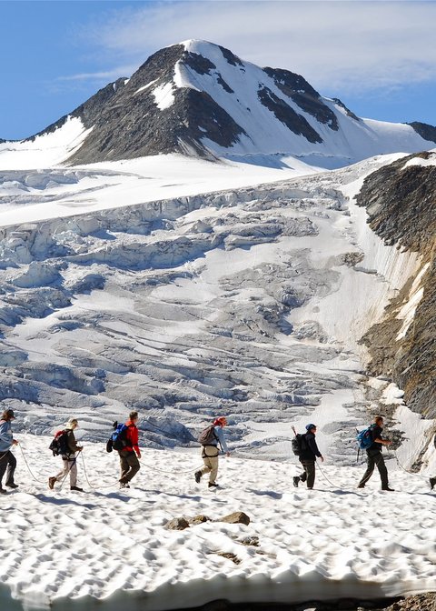 Bilder aus der Sportalm Gruppe von Wanderern auf verschneitem Bergpfad mit Berg im Hintergrund