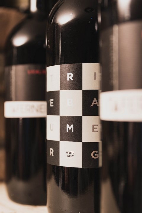 Bilder aus der Sportalm Nahaufnahme von Weinflaschen mit modernen Etiketten vor Ziegelwand