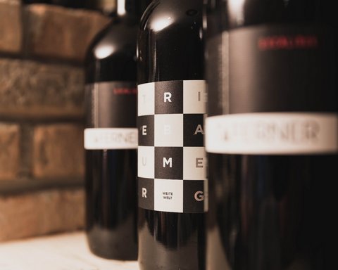 Bilder aus der Sportalm Nahaufnahme von Weinflaschen mit modernen Etiketten vor Ziegelwand