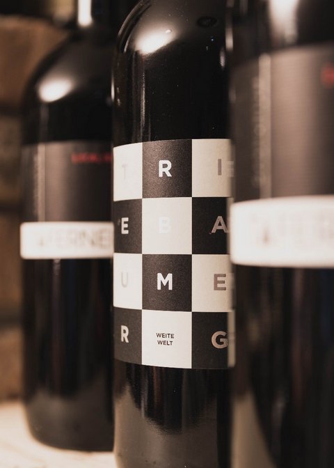 Bilder aus der Sportalm Nahaufnahme von Weinflaschen mit modernen Etiketten vor Ziegelwand