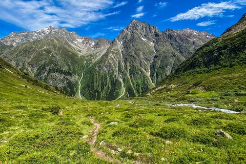 Bilder aus der Sportalm Wanderweg durch grüne Wiesen zu hohen Bergen unter blauem Himmel