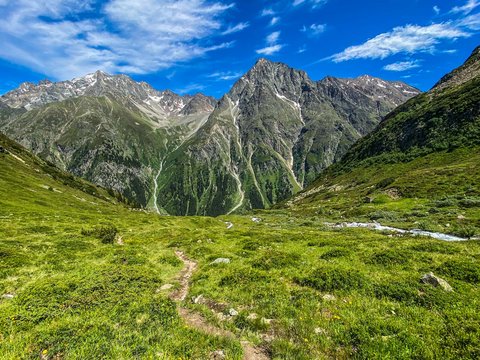 Pictures from Sportalm Hiking trail through green meadows towards tall mountains under blue sky