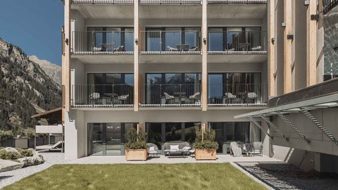 Bilder aus der Sportalm Modernes Hotelgebäude mit Balkonen vor einer Berglandschaft und grünem Rasen