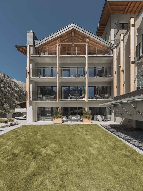 Bilder aus der Sportalm Modernes Hotelgebäude mit Balkonen vor einer Berglandschaft und grünem Rasen