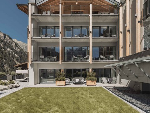 Bilder aus der Sportalm Modernes Hotelgebäude mit Balkonen vor einer Berglandschaft und grünem Rasen