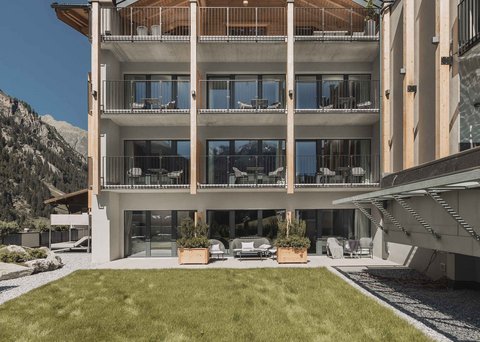 Bilder aus der Sportalm Modernes Hotelgebäude mit Balkonen vor einer Berglandschaft und grünem Rasen