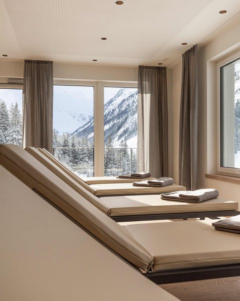 Bilder aus der Sportalm Liegestühle mit Handtüchern vor Fenstern mit Blick auf verschneite Berge