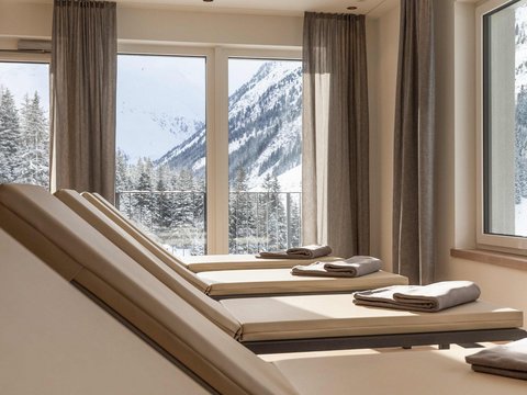 Bilder aus der Sportalm Liegestühle mit Handtüchern vor Fenstern mit Blick auf verschneite Berge