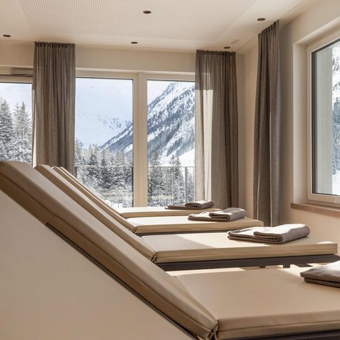 Bilder aus der Sportalm Liegestühle mit Handtüchern vor Fenstern mit Blick auf verschneite Berge