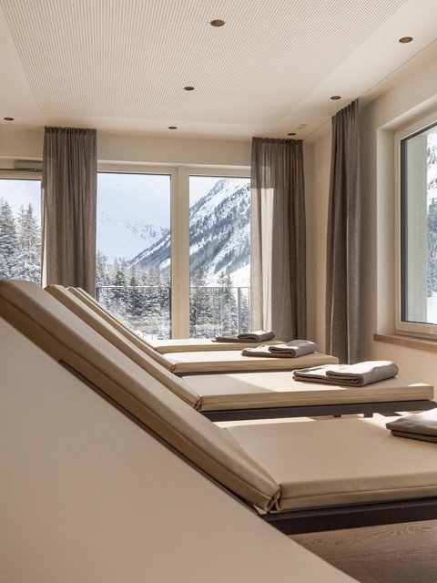 Bilder aus der Sportalm Liegestühle mit Handtüchern vor Fenstern mit Blick auf verschneite Berge