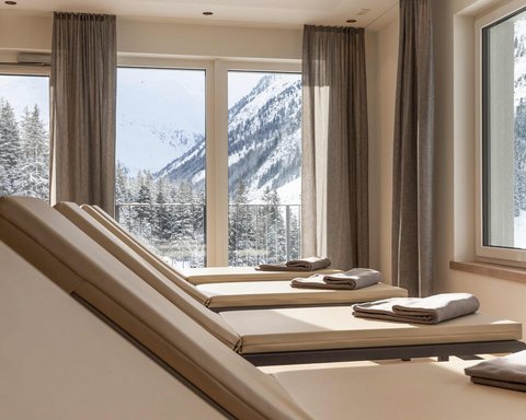 Bilder aus der Sportalm Liegestühle mit Handtüchern vor Fenstern mit Blick auf verschneite Berge