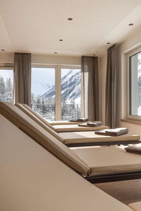 Bilder aus der Sportalm Liegestühle mit Handtüchern vor Fenstern mit Blick auf verschneite Berge