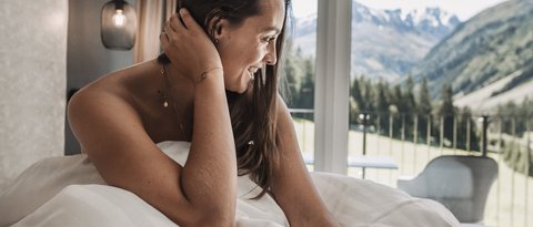 Pictures from Sportalm Woman sitting in bed with mountain view through window