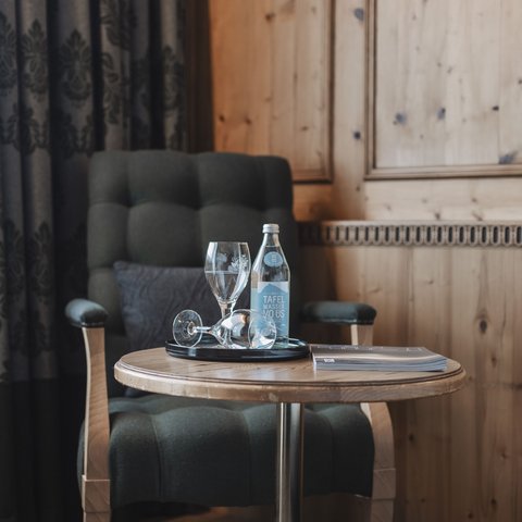 Pictures from Sportalm Armchair beside table with water bottle, glasses and book in wooden room